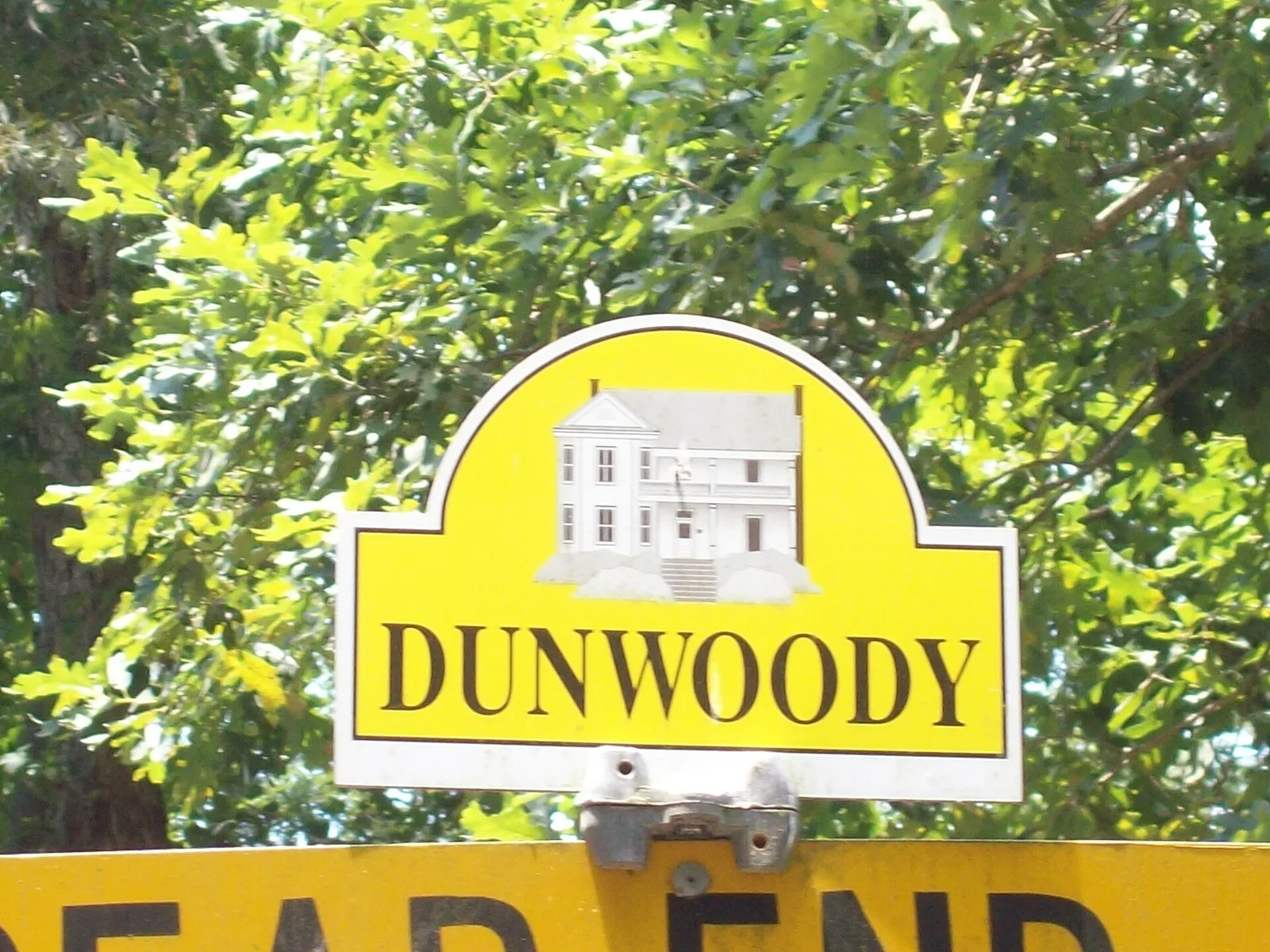 Dunwoody's farmhouse sign topper on a neighborhood street sign